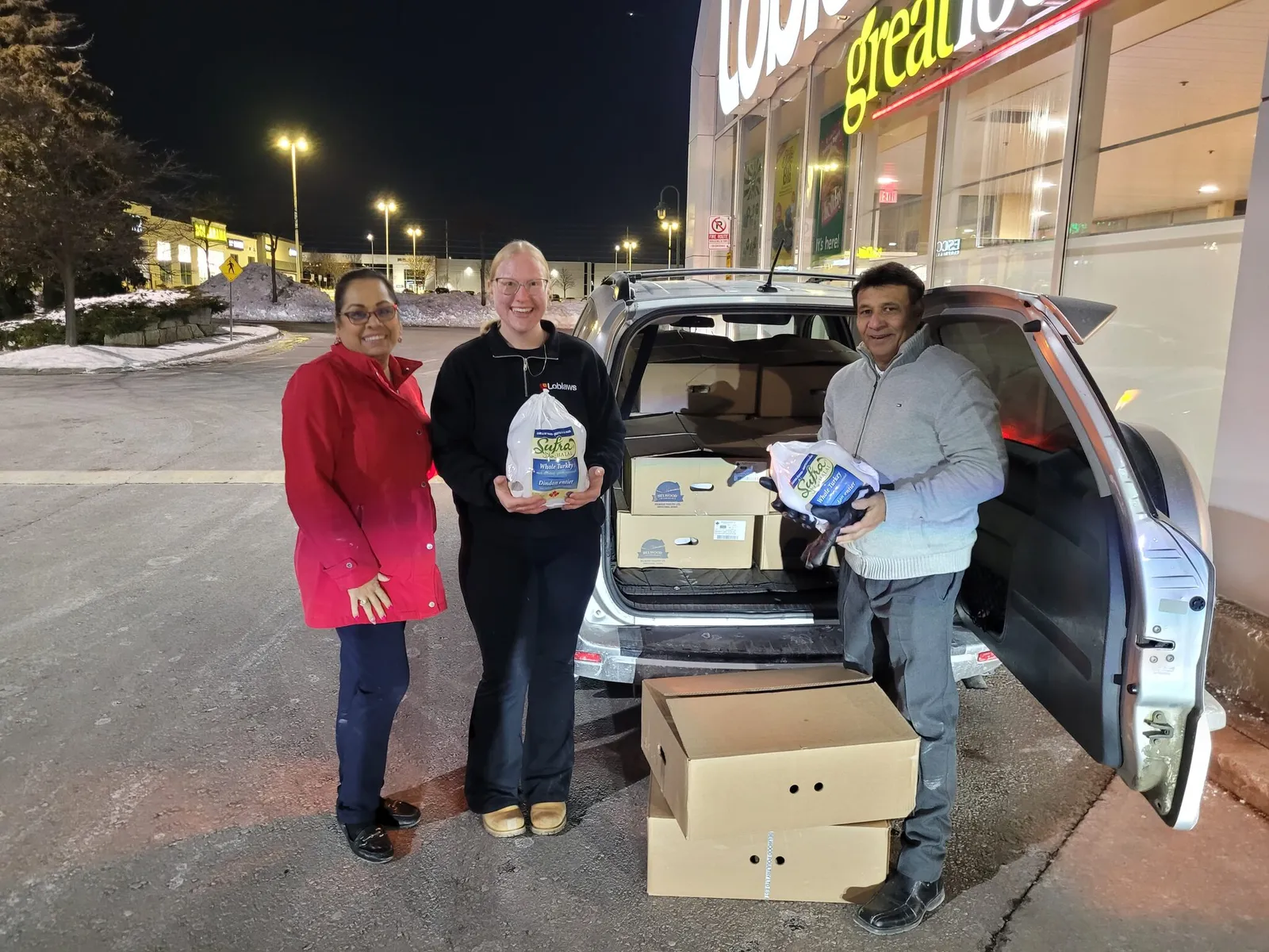 Volunteers collecting donated whole turkeys from Loblaws and loading boxes into a car for families
