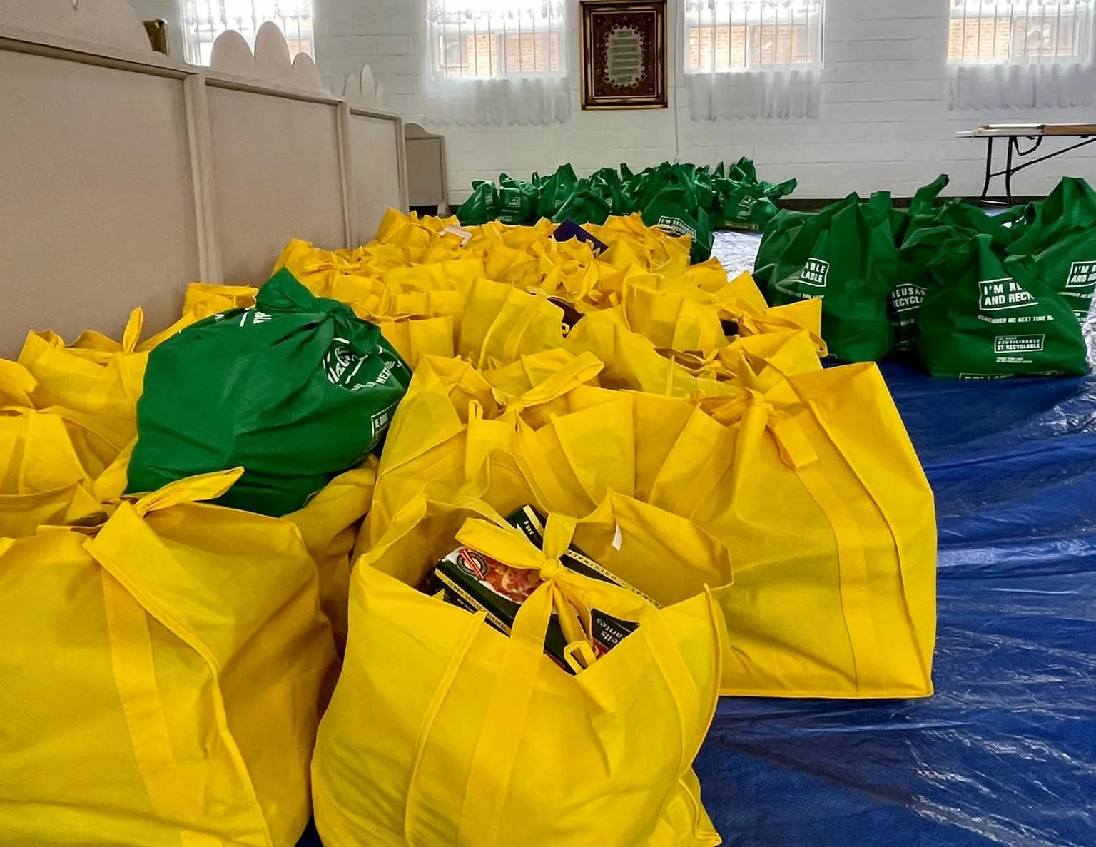 Rows of packed One Love Table hamper bags in a community hall, ready for families